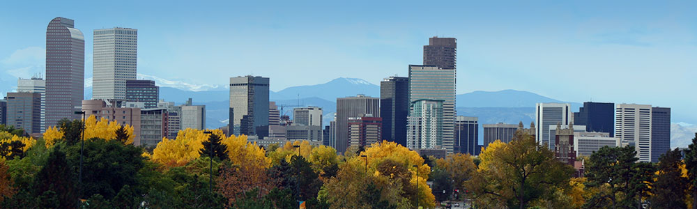 denver skyline with fall trees in the foreground and the Front Range in the background